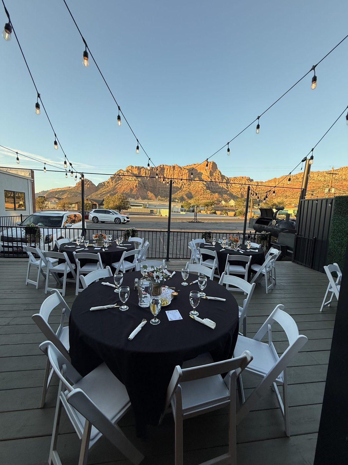 Patio tables under string lights with the mesa behind