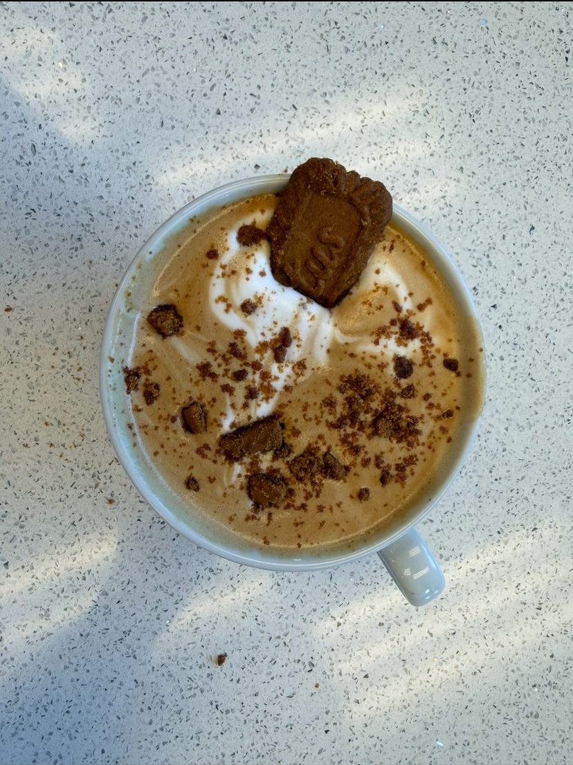 Latte topped with cookie crumble and a cookie
