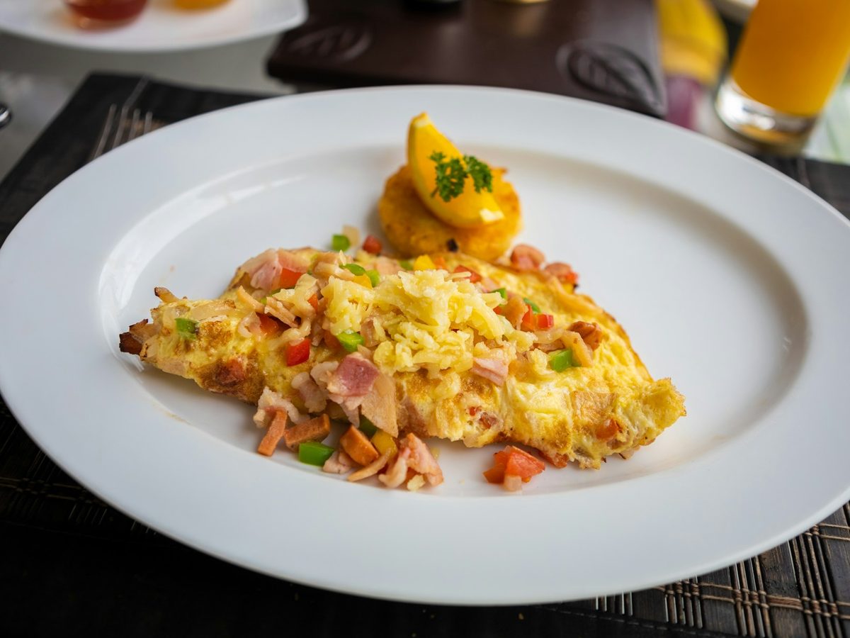 Omelette with peppers and ham on a white plate — illustrative